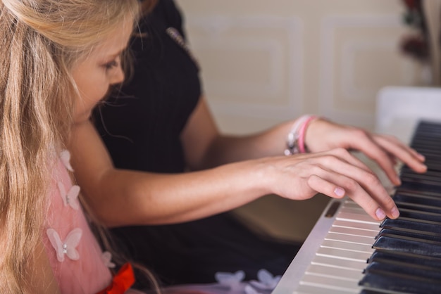 Молодая женщина учит маленькую девочку играть на пианино