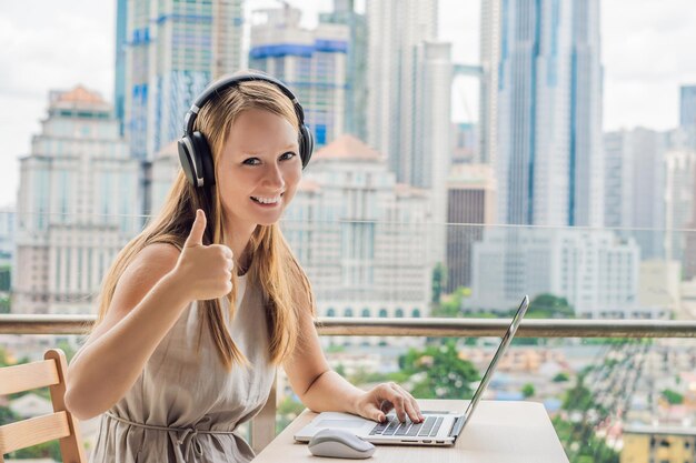 Young woman teaches a foreign language or learns a foreign language on the internet on her balcony