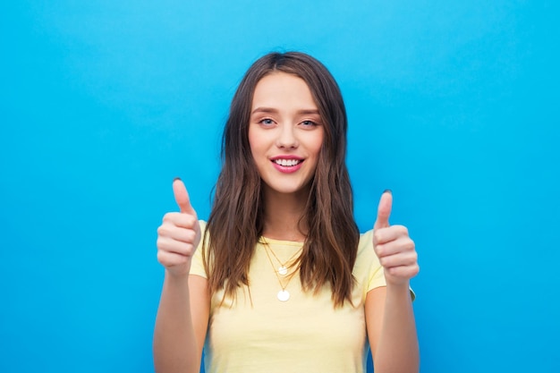 young woman or teenage girl showing thumbs up