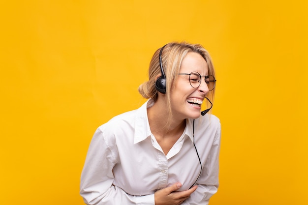 Young woman telemarketer laughing out loud at some hilarious joke, feeling happy and cheerful