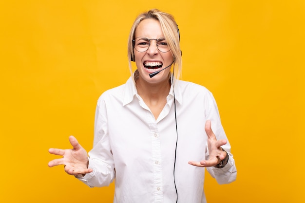 Young woman telemarketer looking angry, annoyed and frustrated screaming wtf or whatÃ¢ÂÂs wrong with you