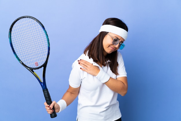 Young woman tennis player over isolated background suffering from pain in shoulder for having made an effort