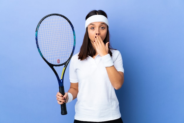Young woman tennis player over isolated covering mouth with hand