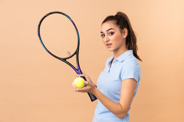 Young woman tennis player over wall