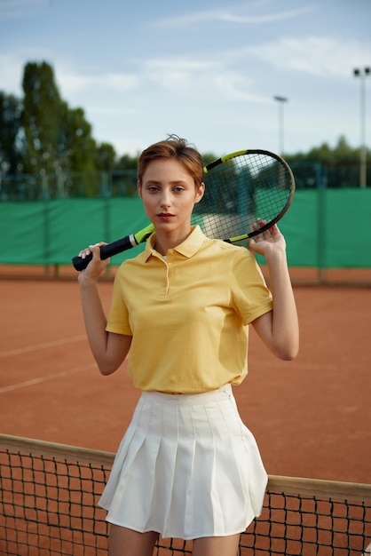 Фото Молодая теннисистка в модной спортивной одежде позирует с ракеткой в сети концепция досуга и спорта на открытом воздухе