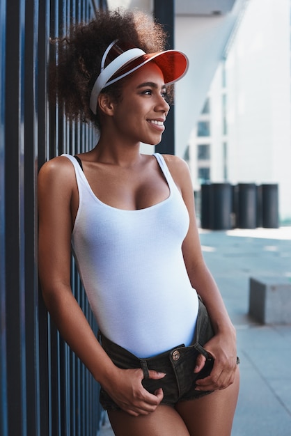 Young woman in tennis visor free style on the street leaning on