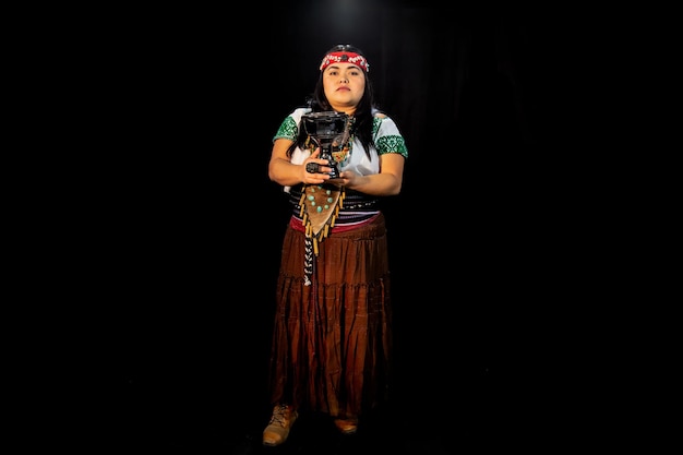 Young woman Teotihuacana, Xicalanca - Toltec in black background, with traditional dress dance with a trappings with feathers and drum