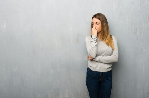 Young woman on textured wall having doubts