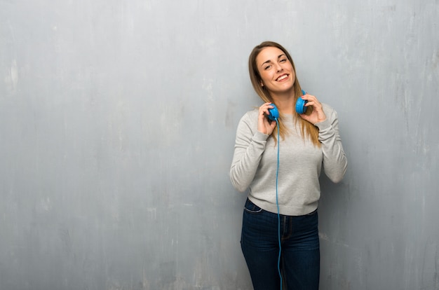 Young woman on textured wall with headphones