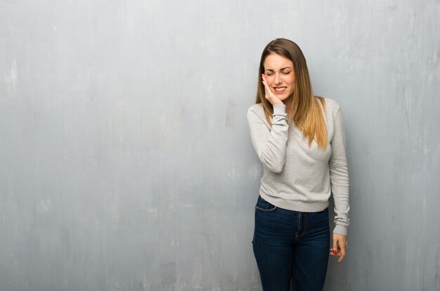 Young woman on textured wall with toothache