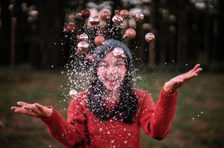 Photo young woman throwing confetti and christmas ornaments in air