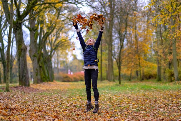 Photo young woman throwing leaves in a heart shape in the air