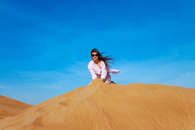 Young woman throwing sand in orande desert