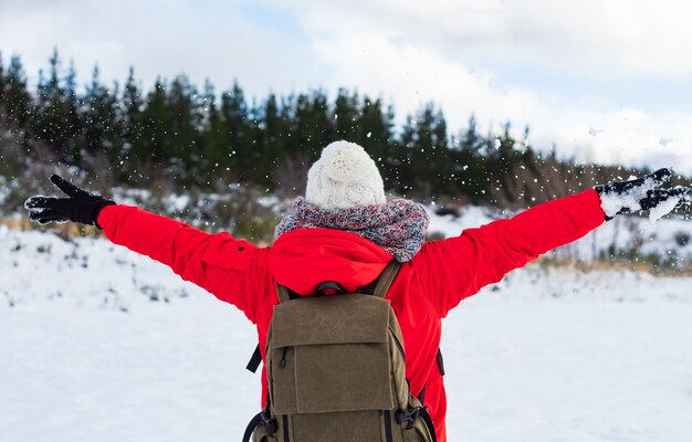 Young woman throwing snow into the air on a sunny winter day,\
back view. feeling of freedom and fun.