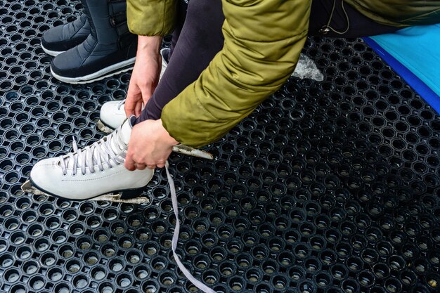 A young woman tied laces on white skates before riding a skating rink