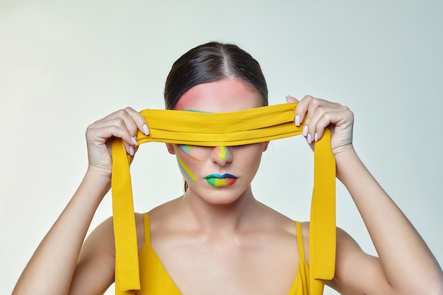 Young woman ties her eyes with a yellow ribbon