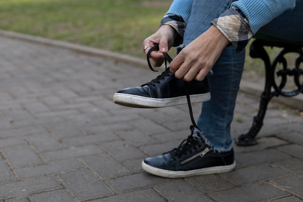 A young woman ties her shoe braids in the park