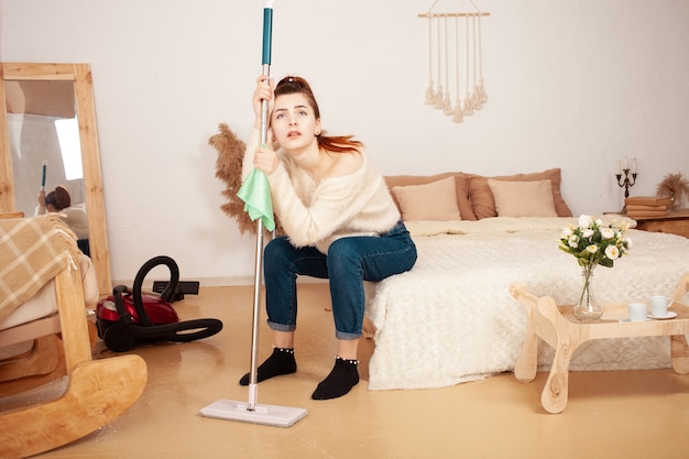 Photo young woman tired after cleaning a woman sits on the bed sad back hurts the woman rests and suffers