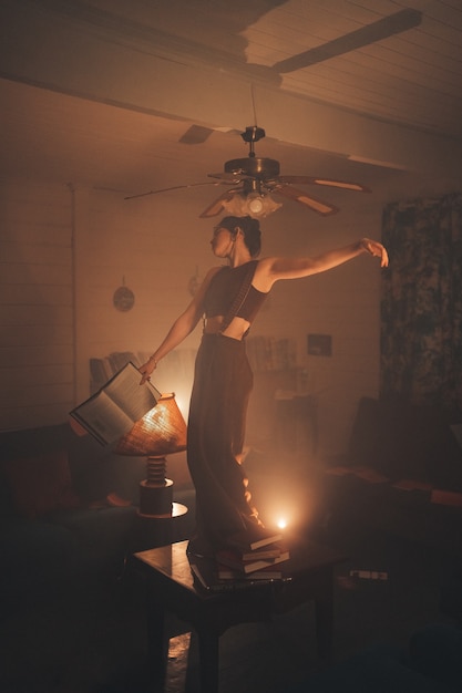 Photo young woman on top of a table holding a book