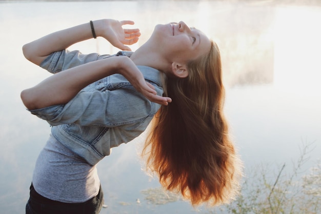 young woman tossing hair at lakeshore