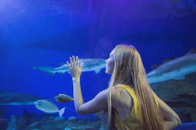 Young woman touches a stingray fish in an oceanarium tunnel