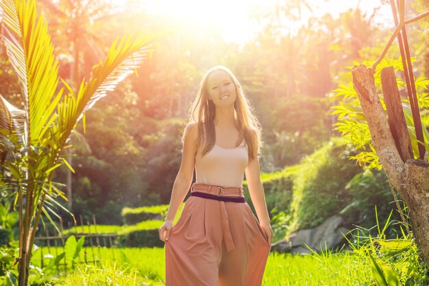 Young woman tourist in the background of rice terraces, Ubud, Bali, Indonesia with sunlight