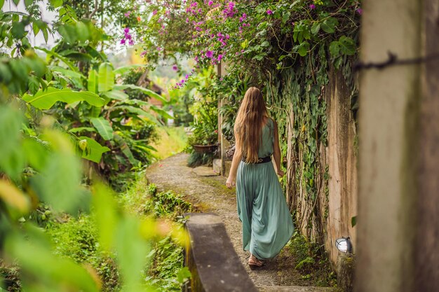 Young woman tourist in Bali walks along the narrow cozy streets of Ubud Bali is a popular tourist destination Travel to Bali concept