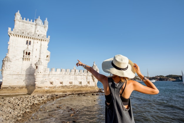 포르투갈 리스본의 강변에 있는 벨렘 타워에서 일몰을 즐기는 젊은 여성 관광객