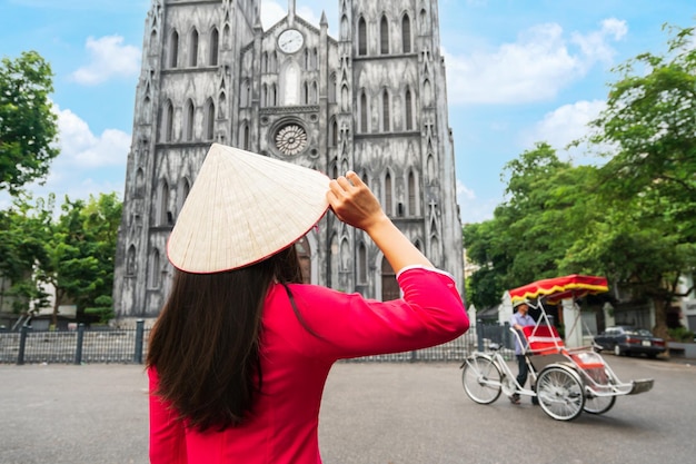 写真 聖ヨセフ大聖堂を観光するアオザイの伝統的なベトナムの衣装を着た若い女性観光客