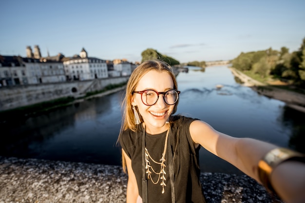 オルレアン、フランスの美しい街並みの背景に自分撮り写真を作る若い女性観光客