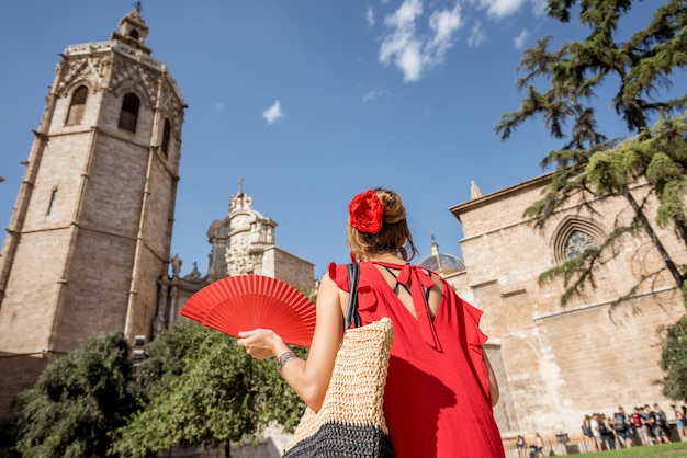 Photo young woman tourist in red dress walking on the central square near the main cathedral in valencia city, spain