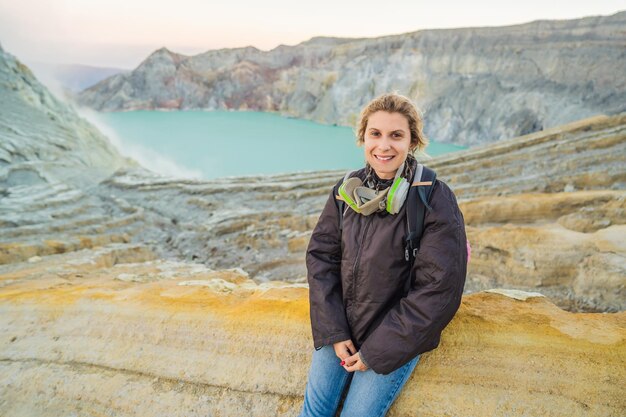 写真 イェン火山の火口の端に座っている若い女性観光客または川のカワ・イェン