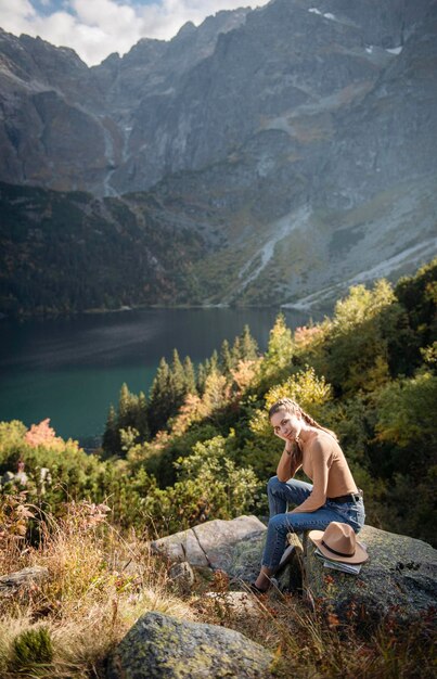 Young woman tourist sitting on the mountain peak and beautiful mountains