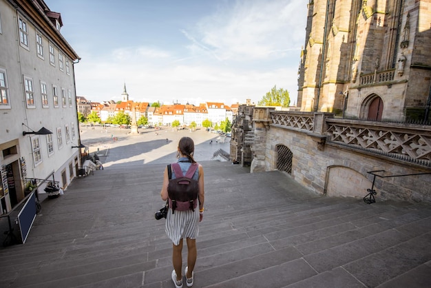 Young woman tourist standing back on the stairs of Mary Domberg cathedral in Erfurt city, Germany