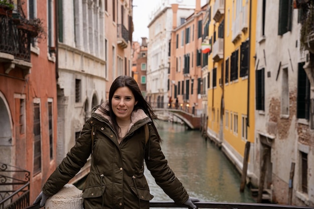 Young woman tourist on a Venice canal bridge amidst colorful facades