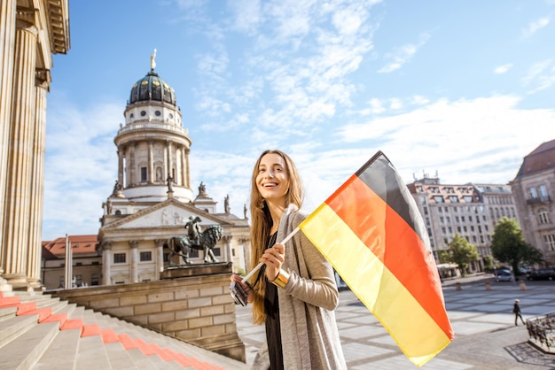 베를린 콘서트 하우스 근처 계단에서 독일 국기를 들고 걷는 젊은 여성 관광객