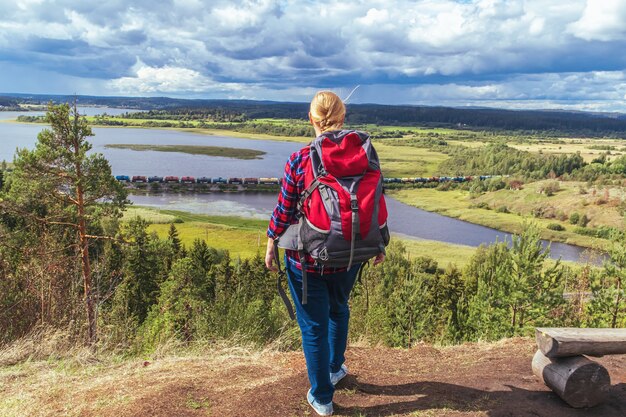 Young woman tourist with a backpack on the top of the mountain. Hiking,  recreation,  outdoor walks, healthy lifestyle.