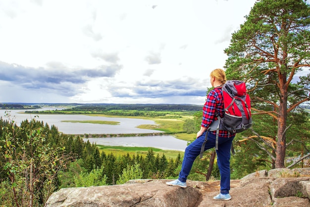 Young woman tourist with a backpack on the top of the mountain