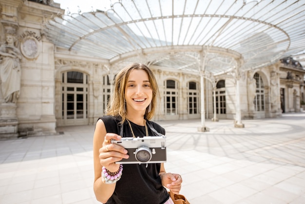 Young woman tourist with photo camera standing near the old Opera building in Vichy city in France