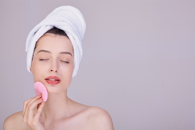 Young woman in a towel after a shower holds a cosmetic disc