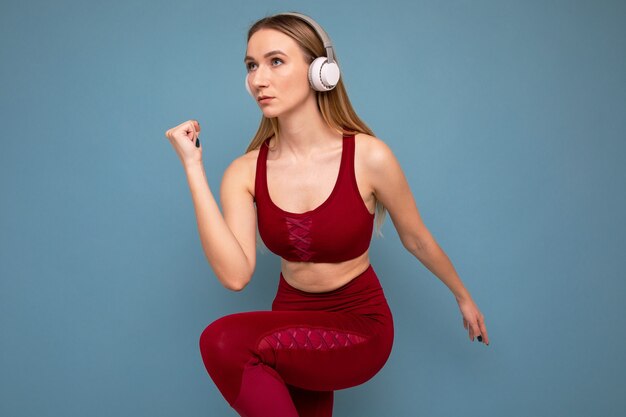 A young woman in a tracksuit and headphones runs on a blue background