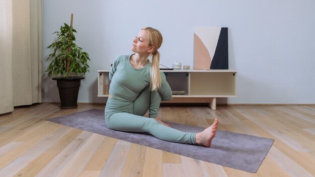 A young woman in a tracksuit during an indoor yoga workout