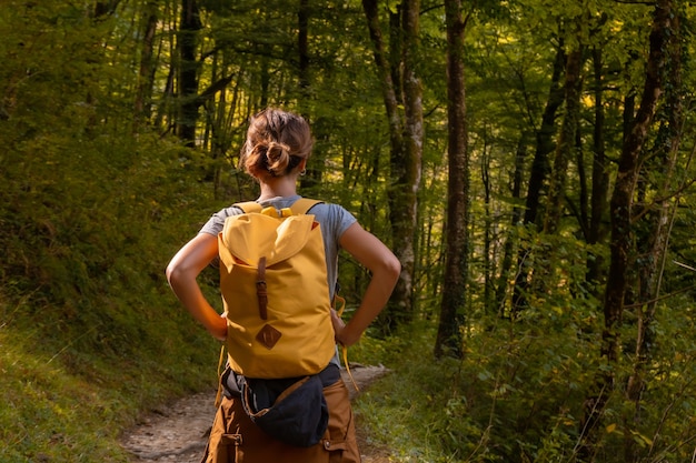 A young woman on the trail heading to Passerelle de Holtzarte de Larrau in the forest or jungle of Irati, northern Navarra in Spain and the Pyrenees-Atlantiques of France