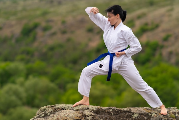 Young woman training for martial arts outdoors on a rock