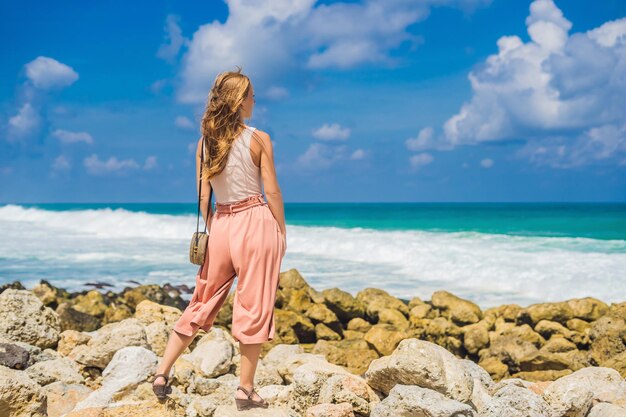 Young woman traveler on amazing Melasti Beach with turquoise water Bali Island Indonesia