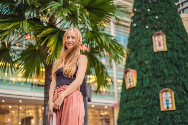 Young woman traveler on the background of Christmas Tree and Palm Trees Decorated in tropical holiday location