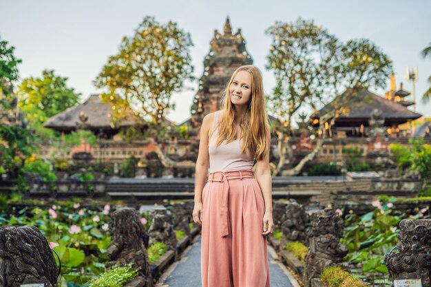 Young woman traveler in the background of Pura Taman Kemuda Saraswati Temple in Ubud, Bali island, Indonesia.