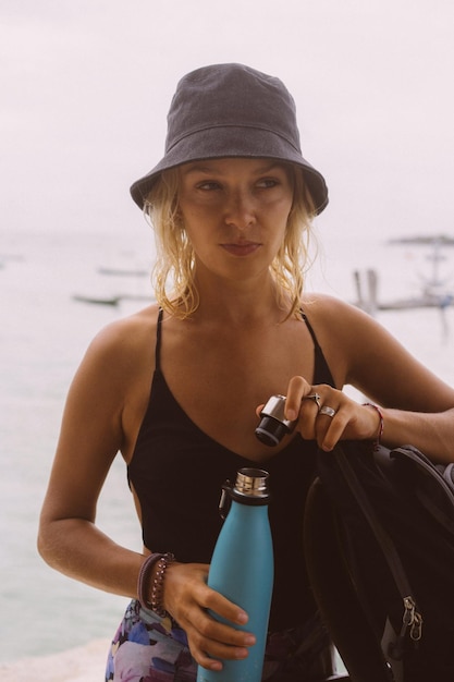 Young woman traveler drinks water from a colored bottle.