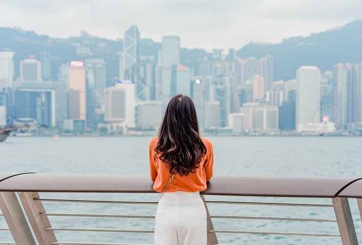 Photo young woman traveler enjoying at hong kong cityscape downtown over victoria harbour