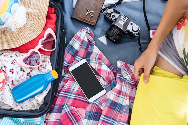 가방, 여행 및 휴가 개념에서 그녀의 옷과 물건을 포장하는 젊은 여성 여행자